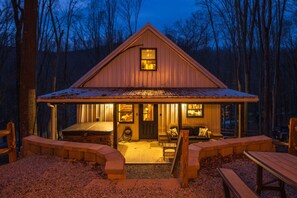Une cabane en bois avec un porche, un espace salon couvert et une petite table.