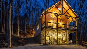 A two-story wooden cabin with a stone foundation, a balcony, and a stone wall entrance. - New Amish built cabin opening up March 14, 2025 near Hocking Hills/Tar Hollow St.Forest (Londonderry)
