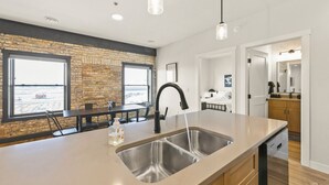 Een moderne keuken met een groot eiland, een inbouwspoelbak en een eethoek met uitzicht op het strand.