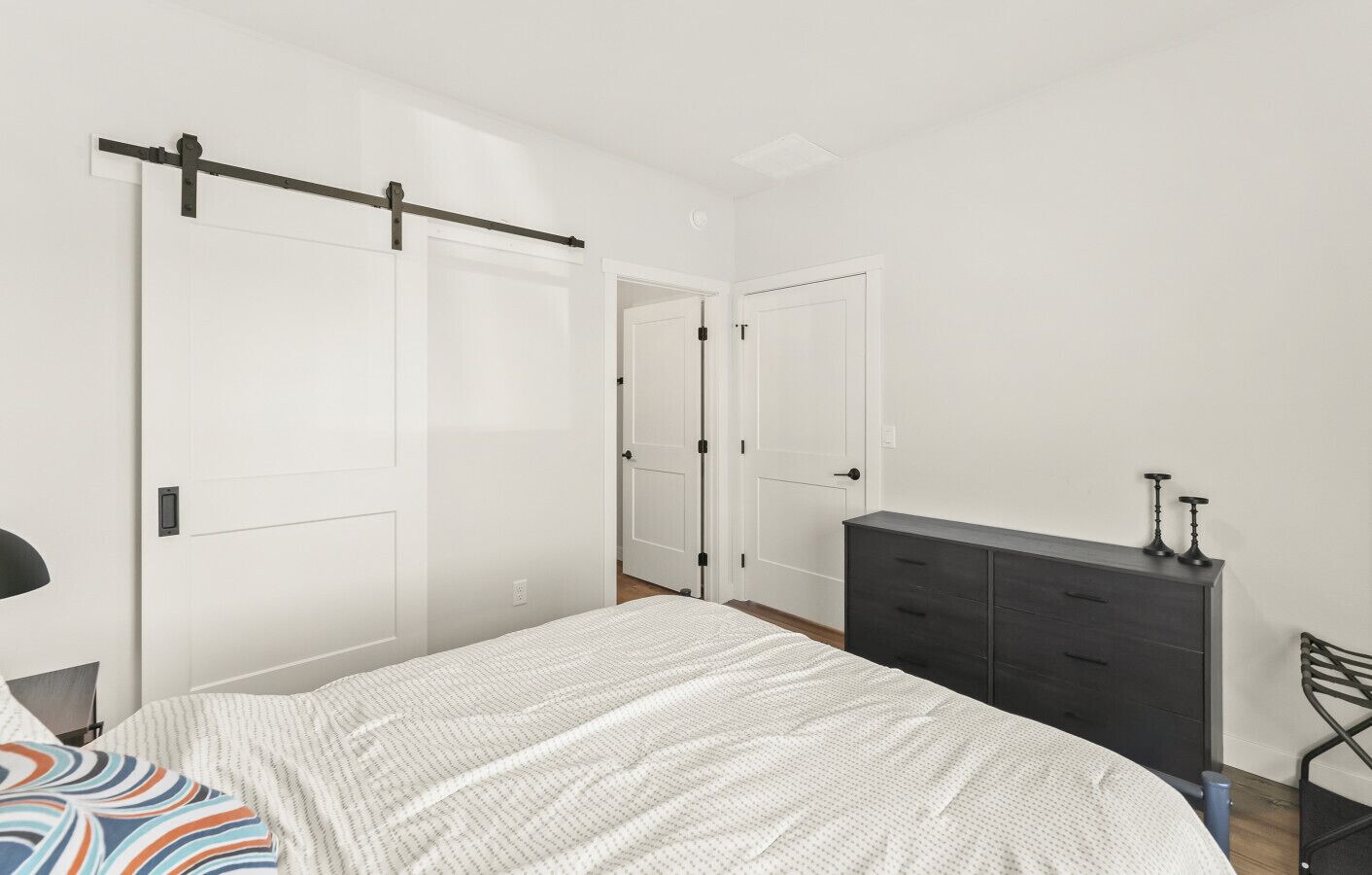 A bedroom with a bed, a dresser, and two white doors.
