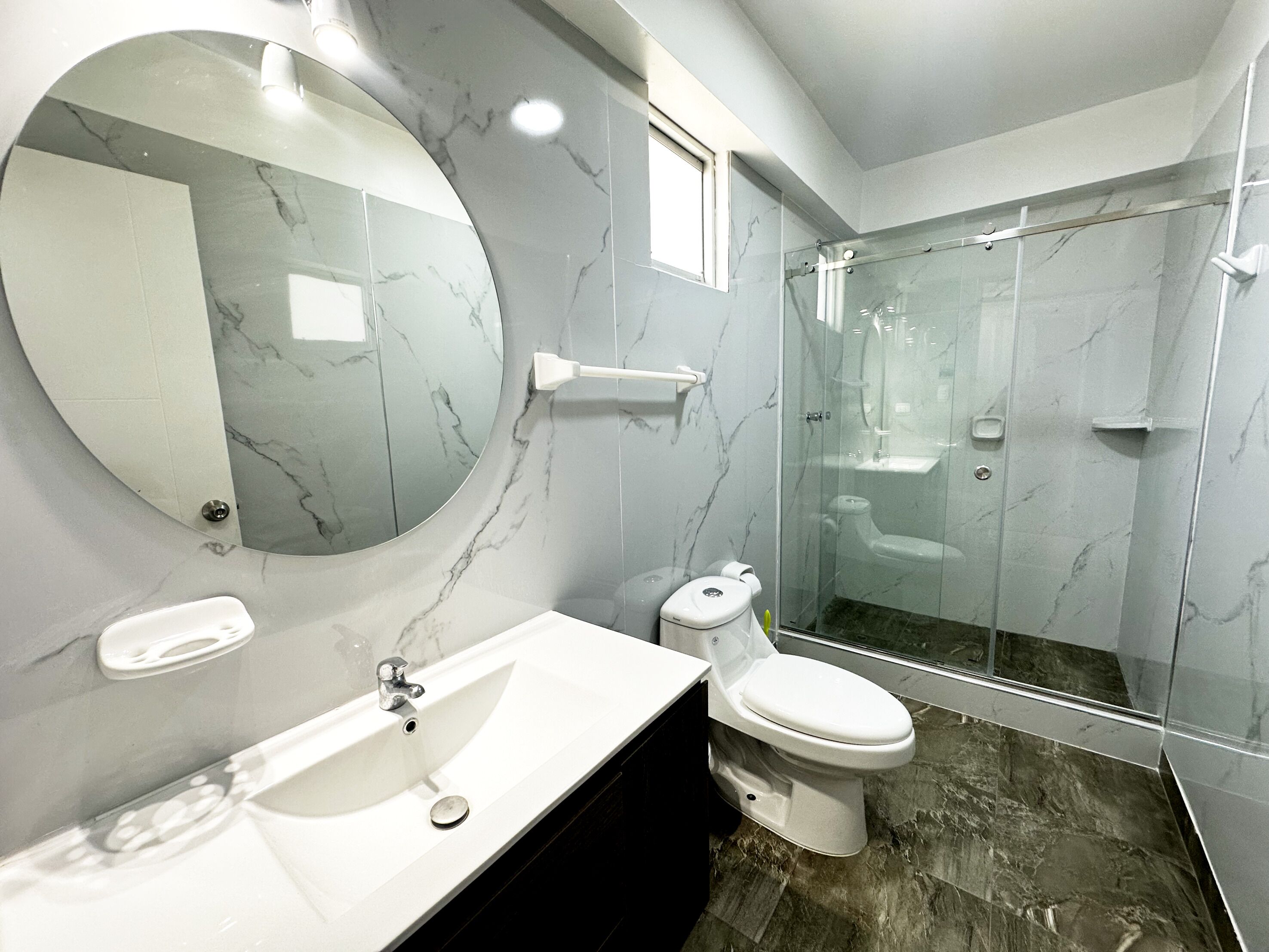A modern bathroom with a marble sink, toilet, and shower.