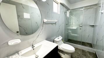 A modern bathroom with a marble sink, toilet, and shower.