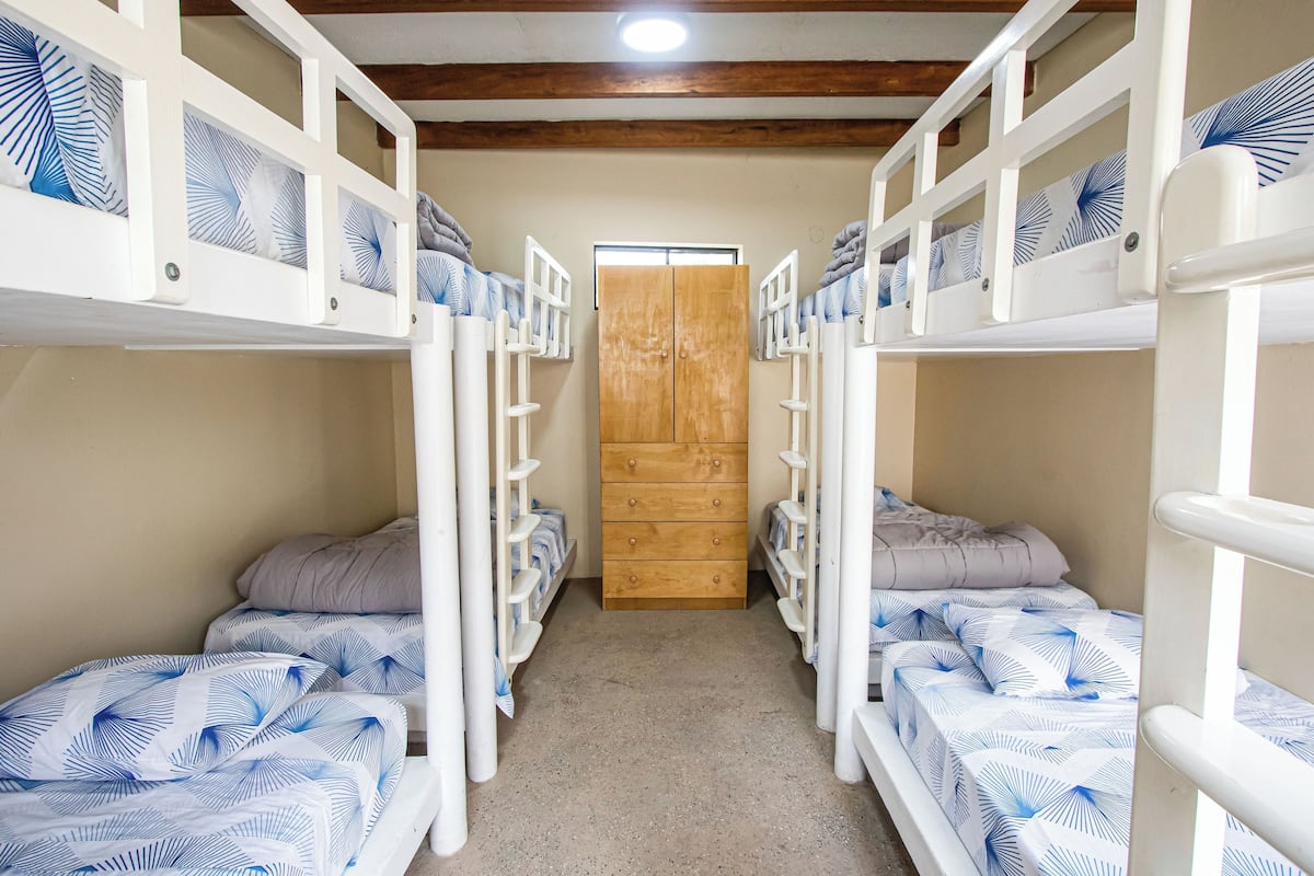 A bunk bed room with a wooden wardrobe and a window.