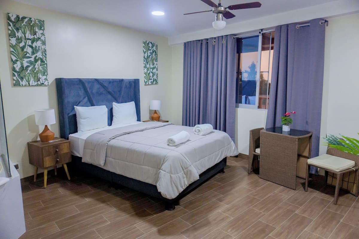 A hotel room with a bed, bedside tables, a desk, and a chair.