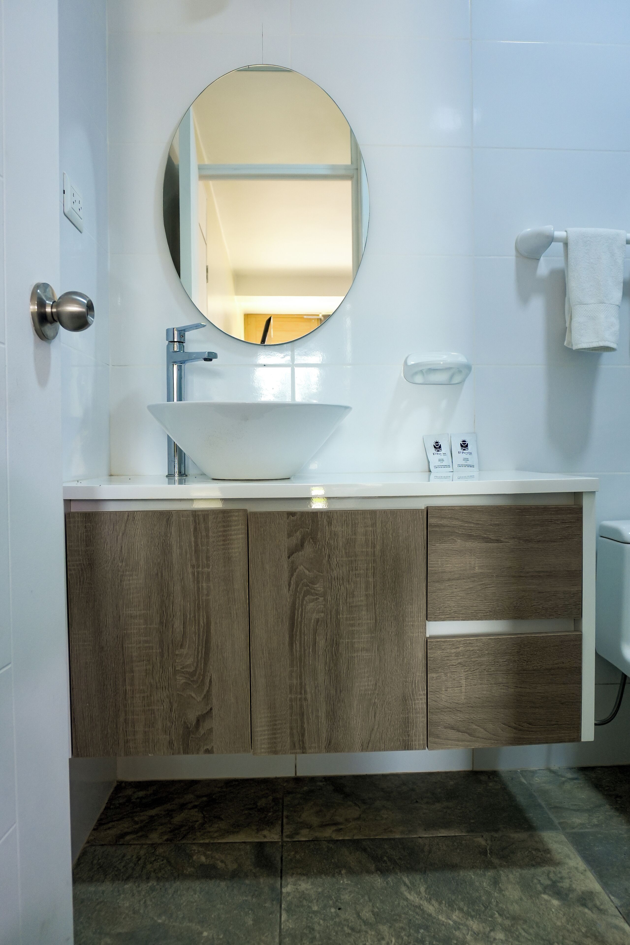 Une salle de bain avec un lavabo blanc, un meuble-lavabo en bois et un miroir.