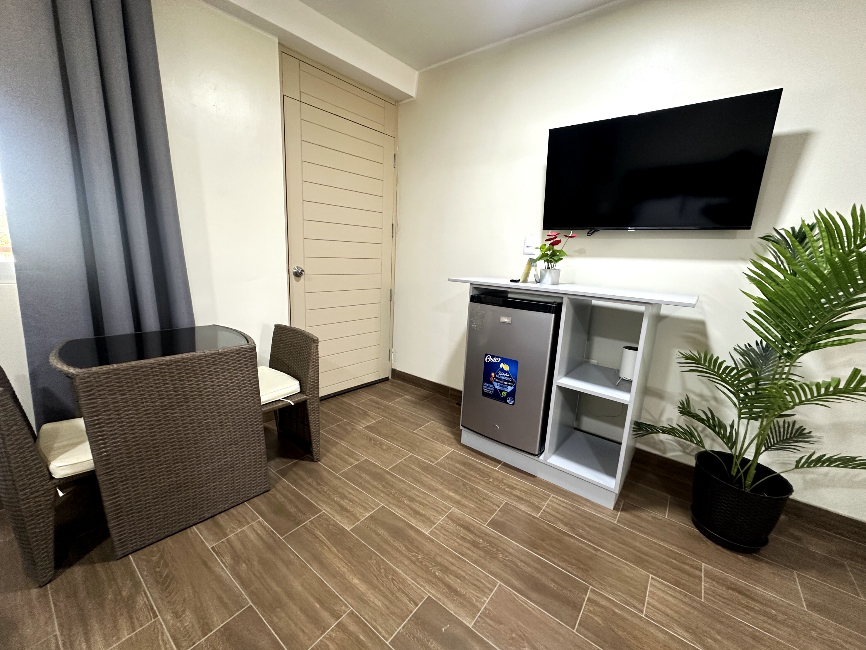 A compact kitchenette with a built-in refrigerator, a small countertop, and a wall-mounted TV.