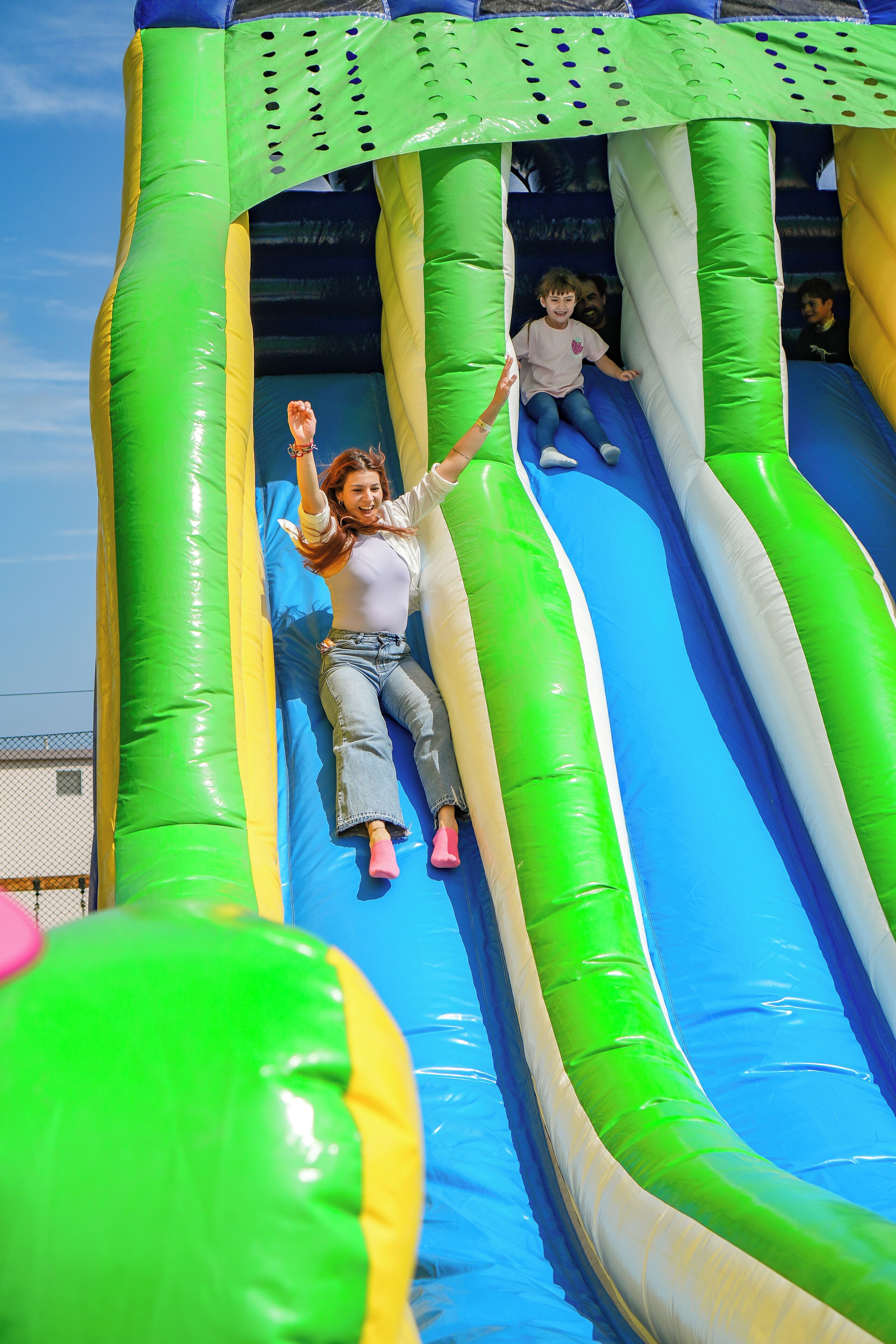 An inflatable slide with green and blue colors and a netted top.