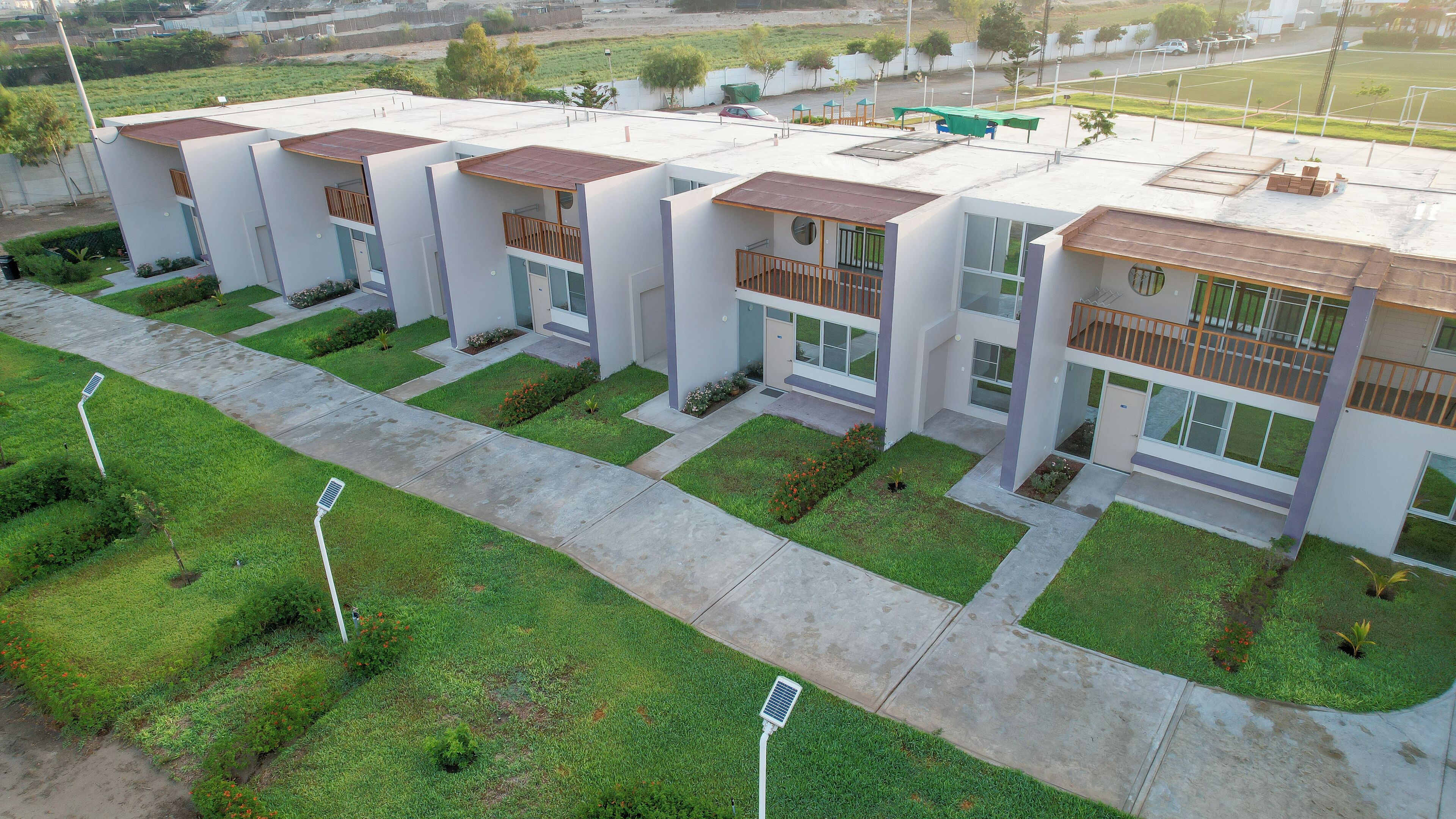 A modern residential complex with multiple two-story buildings, each featuring balconies and large windows.