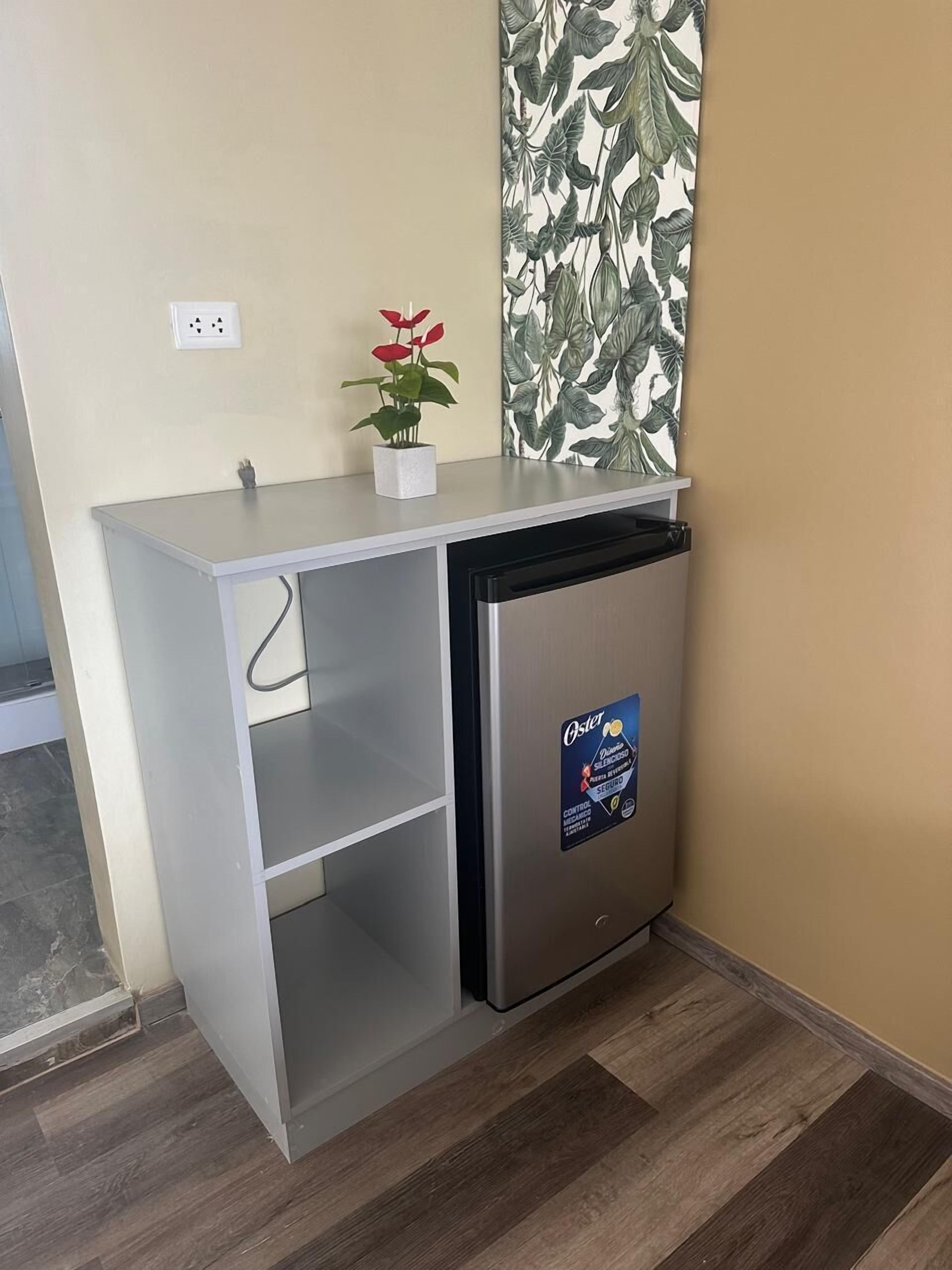 Uma cozinha compacta com geladeira embutida, bancada pequena e um vaso de planta.
