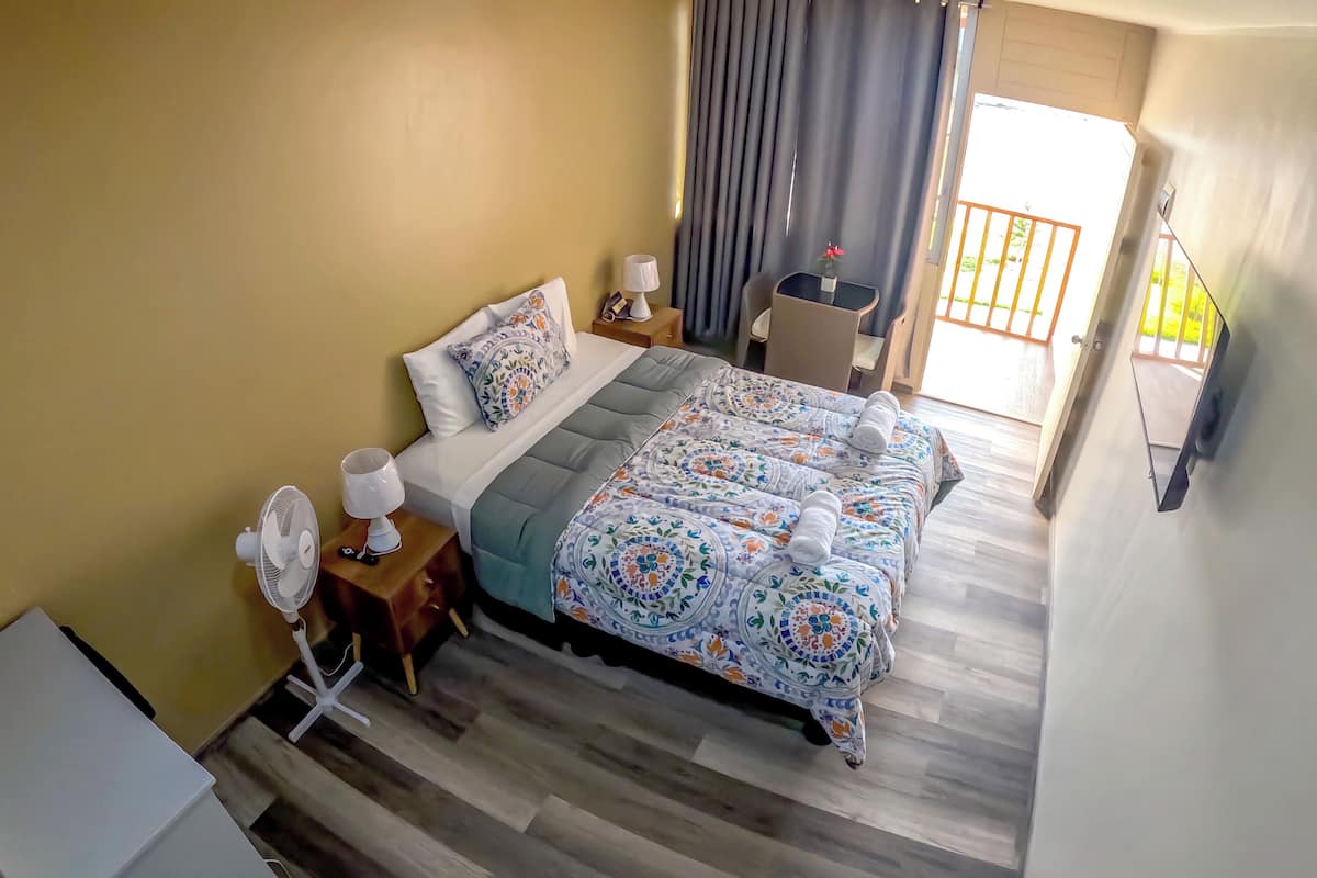 A hotel room with a bed, bedside tables, a desk, and a chair.