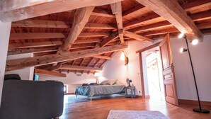 A room with a sloped wooden ceiling, a bed with a headboard, a bedside table, a lamp, a floor lamp, and a large window. - Casa Lounell Swimming pool-SPA-Sauna-Games room, panoramic view   (Graulhet)
