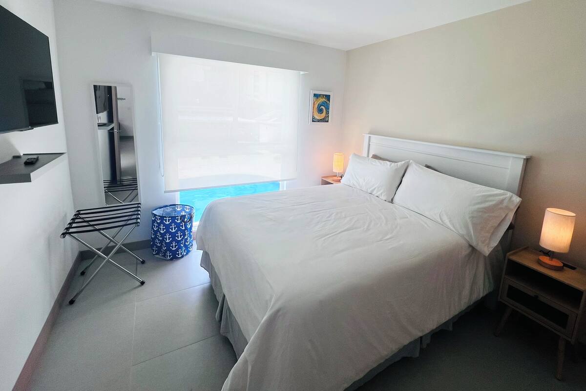 Habitació d'hotel amb un llit, televisió, finestra amb vistes, làmpada i taula petita.
