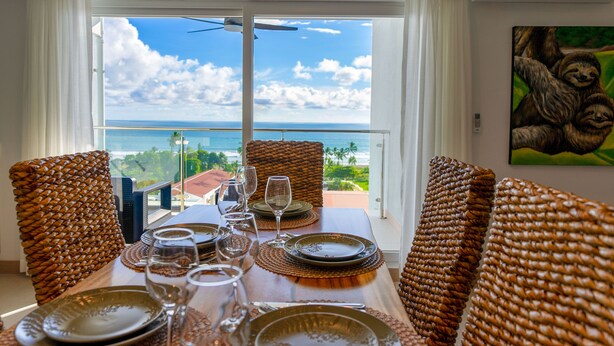 Un coin repas avec une table dressée pour quatre personnes, offrant une vue imprenable sur l’océan.