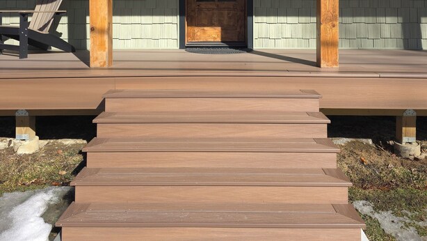 Une terrasse en bois mène à une porte d’entrée surmontée d’une fenêtre.