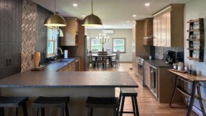 Une cuisine moderne dotée d’un îlot central, de luminaires suspendus et d’un coin repas agrémenté d’un lustre.