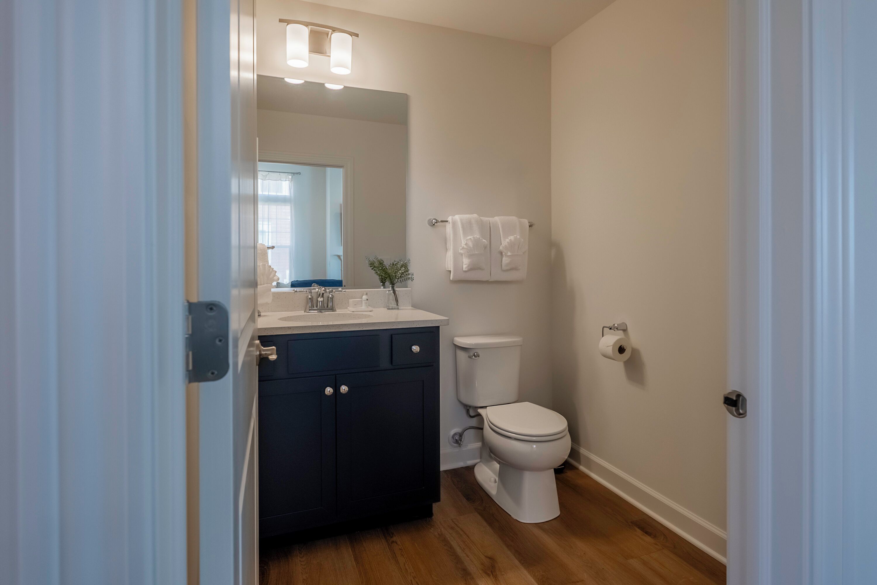 A bathroom with a dark blue vanity, white toilet, and a mirror above the sink.