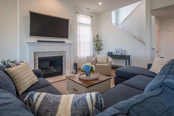 A modern living room with a fireplace, a television mounted above it, and a staircase leading to another level. - 2708 Harbor Court (Delavan)