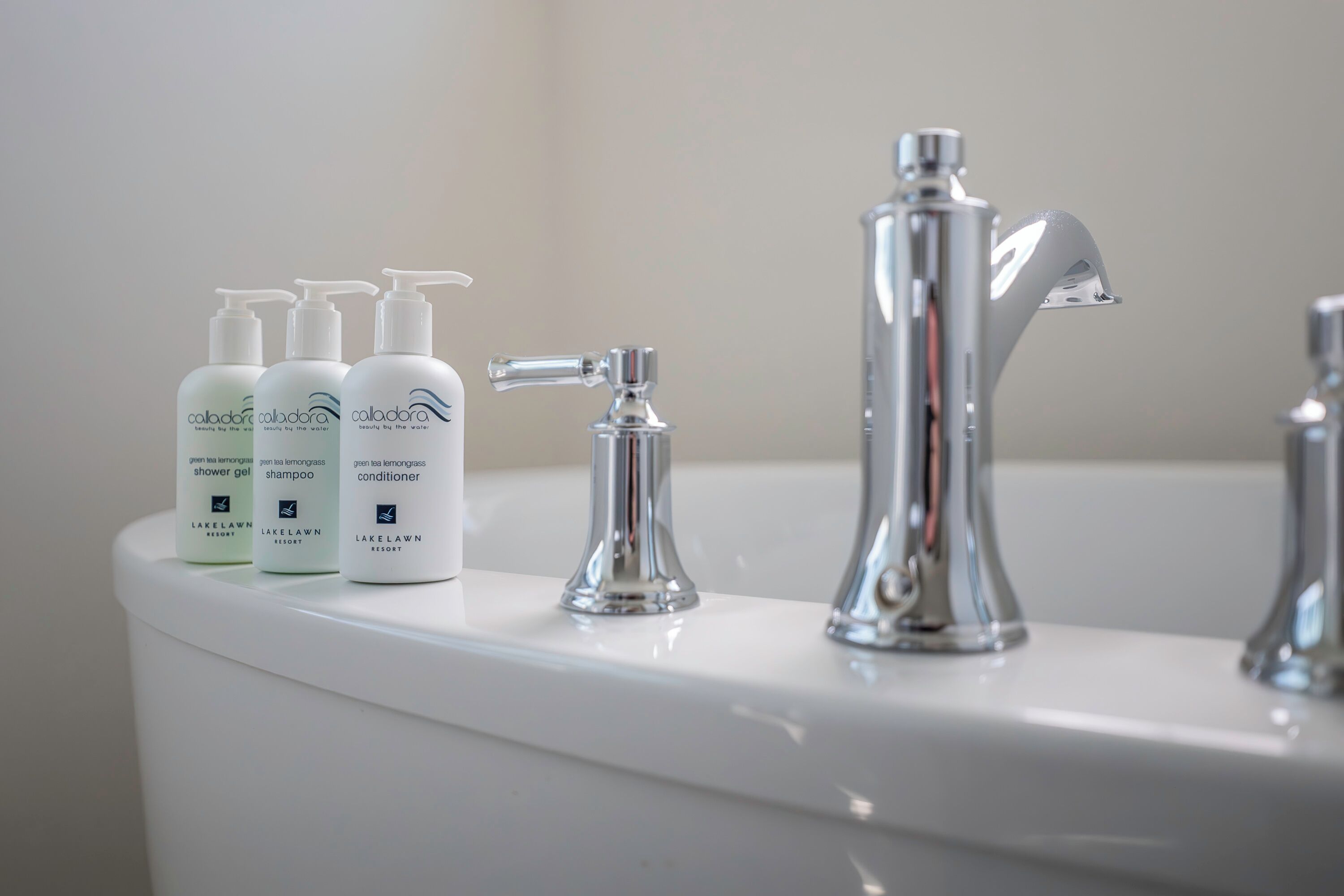 Ein Badezimmer mit Waschbecken, modernem Wasserhahn und drei Flaschen Toilettenartikel vom Caladonia Resort.