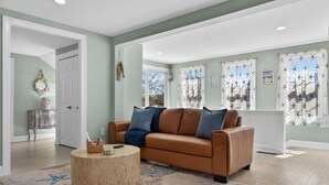A living room with a brown leather sofa, a round wooden coffee table, and a patterned rug.