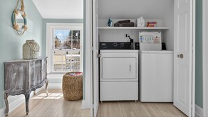 A laundry room with a washer and dryer, a basket, and a small table with a decorative item.