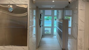 Un couloir aux murs de marbre et une porte en verre donnant sur un espace extérieur.
