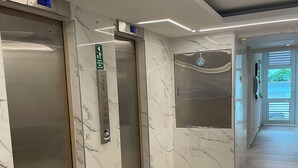Un espace d’ascenseur moderne avec des murs en marbre et un écran numérique.