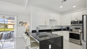 A modern kitchen with white cabinets, stainless steel appliances, and a black countertop island.