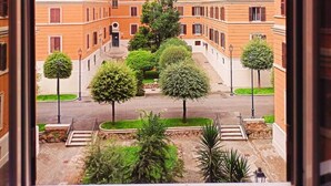 A view of a courtyard with a central staircase, surrounded by multi-story buildings with uniform architecture. - Apartment a stone's throw from S.Giovanni (Roma)
