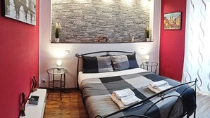 A bedroom with a bed, bedside tables, a desk, and a large wall-mounted artwork. - Apartment a stone's throw from S.Giovanni (Roma)