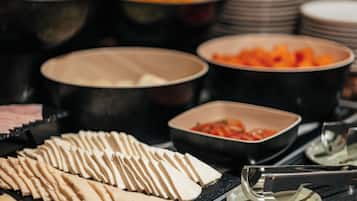 A buffet with various food items including sliced cheese, fruits, and vegetables.