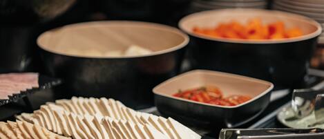 A buffet with various food items including sliced cheese, fruits, and vegetables.