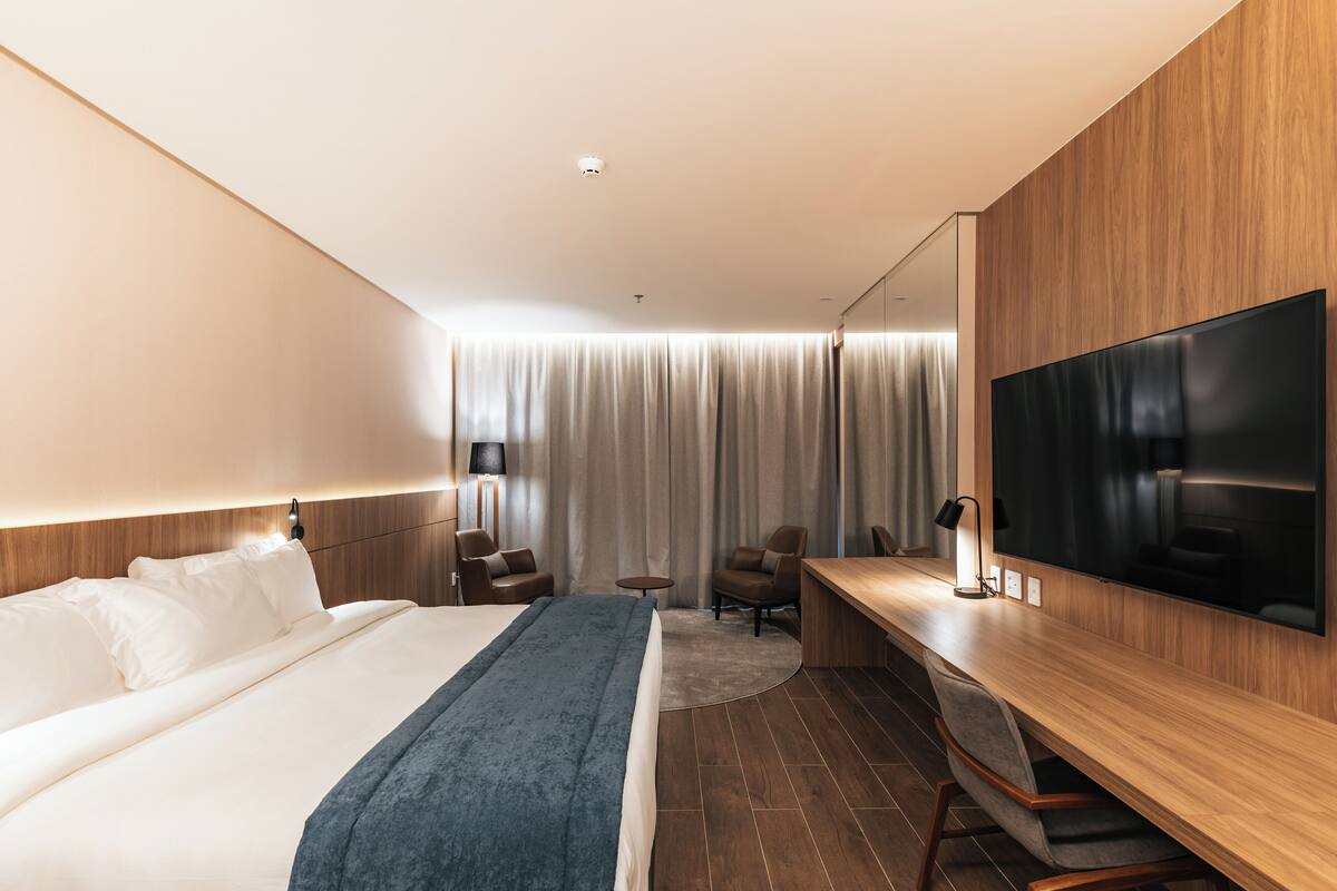 Ein modernes Hotelzimmer mit einem großen Bett, einem Schreibtisch, einem Flachbildfernseher und einer Sitzecke.