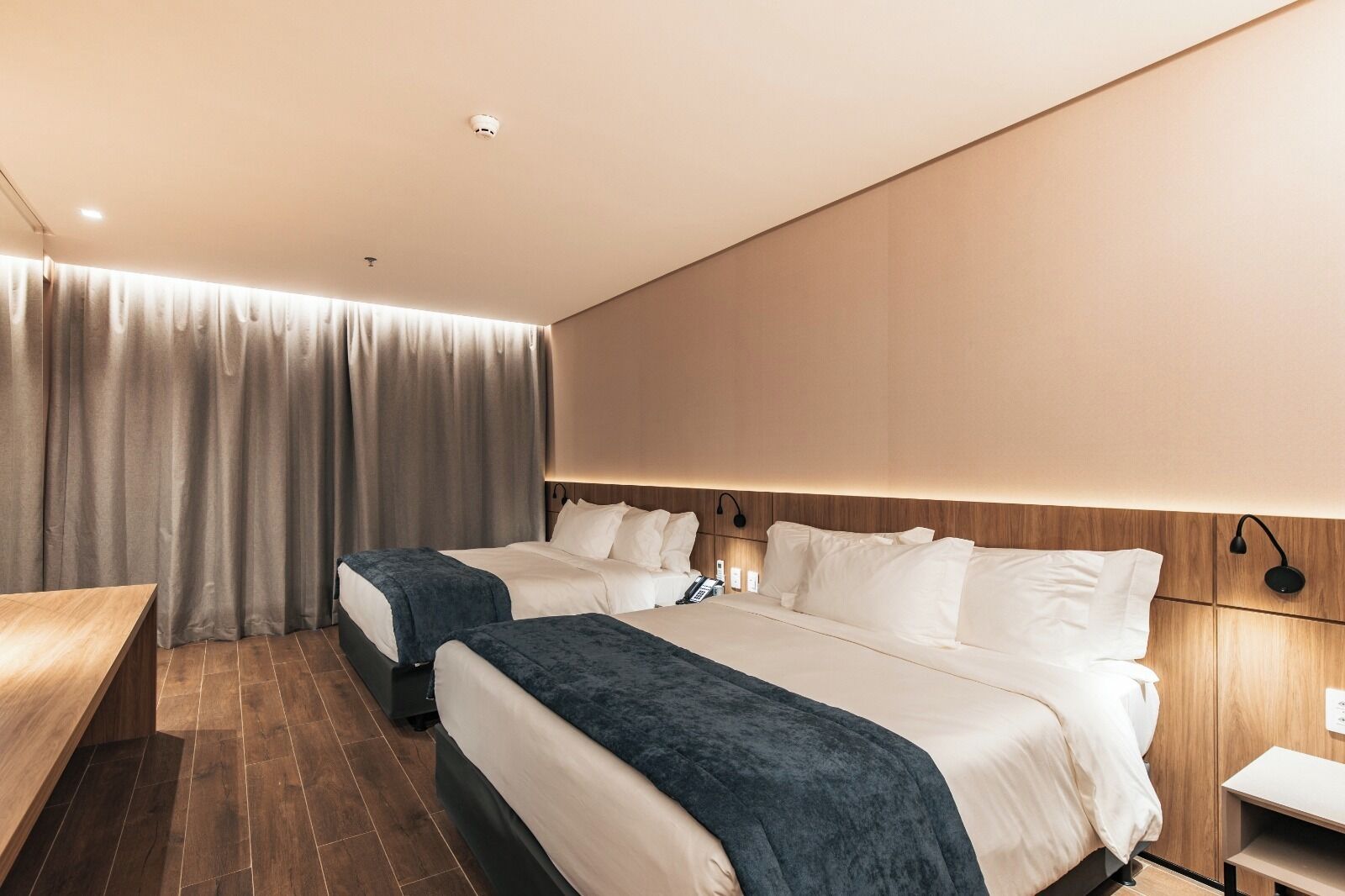 Habitación de hotel con dos camas, un escritorio y una cortina.