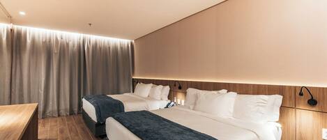 Habitación de hotel con dos camas, un escritorio y una cortina.