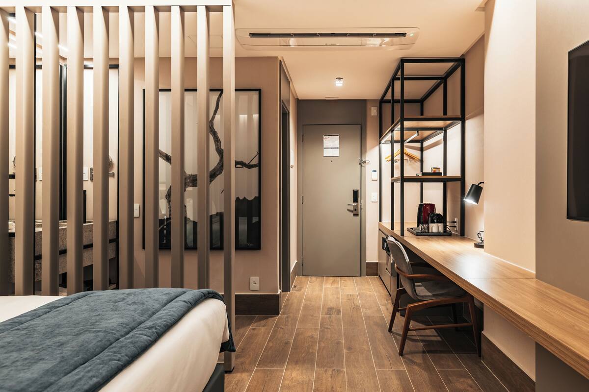 Ein modernes Hotelzimmer mit einem Bett, einem Schreibtisch und einer Regallösung.