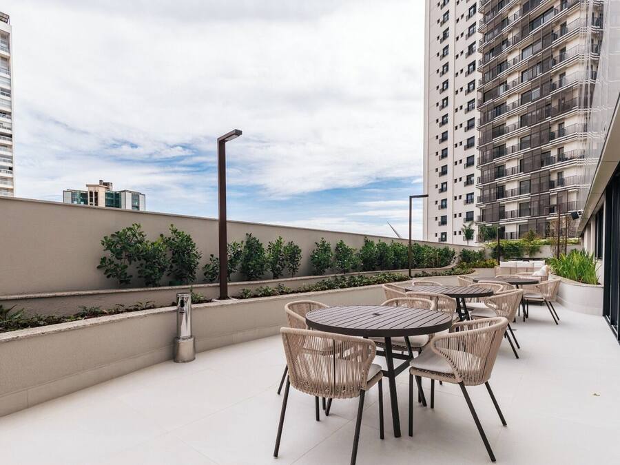 A rooftop patio with outdoor seating, a view of surrounding buildings, and a clear sky.