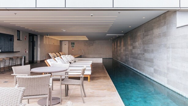 Ein moderner Poolbereich im Innenbereich mit Liegestühlen und einer Bar.