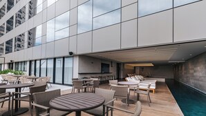 Eine Dachterrasse mit Sitzgelegenheiten im Freien, einem Pool und einer modernen Gebäudefassade.