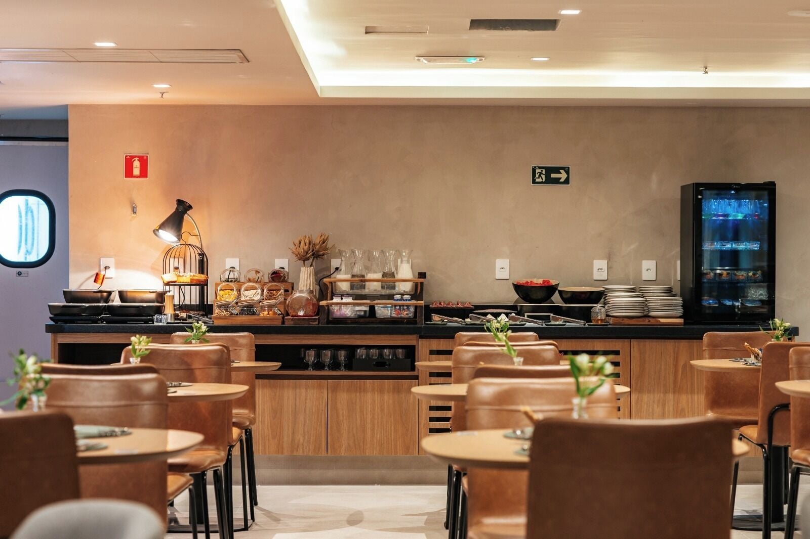 Una cafetería moderna con mostrador, zona de estar y refrigerador.