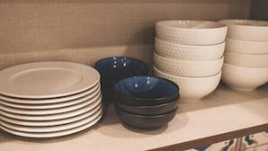 A stack of white plates and bowls on a shelf.