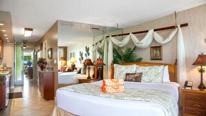 A hotel room with a large bed, a wooden headboard, a nightstand with a lamp, and a view of the hallway. - Maui Kaanapali Villas MKV-C152 by KBM (Kaanapali)