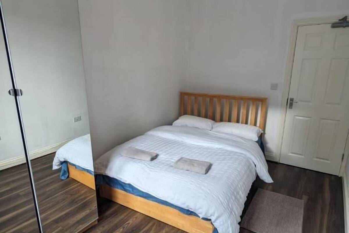 A bedroom with a wooden bed, a large mirror, and a white door.