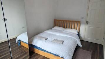 A bedroom with a wooden bed, a large mirror, and a white door.