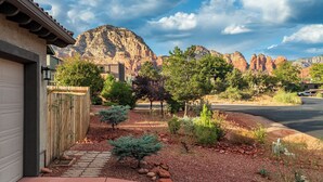 A residential area with a house, a paved driveway, and a mountain backdrop. - Stylish West Sedona Oasis. Hot Tub, E-BIKES & Kids Play Area (Sedona)
