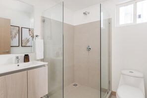 A modern bathroom with a glass-enclosed shower, a white sink, and a toilet. - Viva Jaco (Jacó)