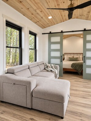 Een modern interieur met een modulaire bank, een bed met hoofdeinde en een plafondventilator.