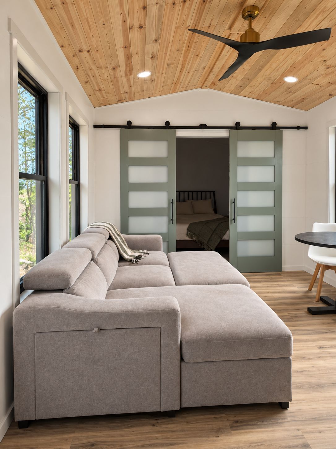 A modern living room with a sectional sofa, a dining table, and a ceiling fan.
