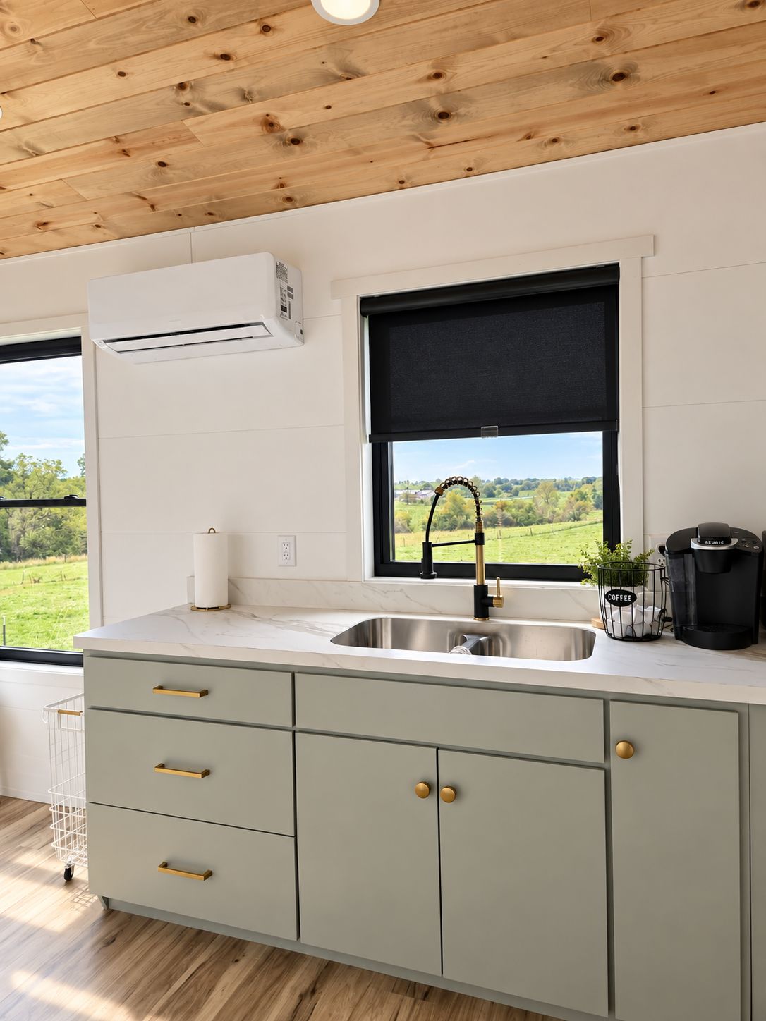 A modern kitchen with a built-in sink, a window with a view of greenery, and a coffee maker on the counter.
