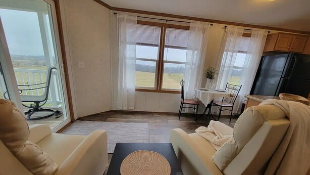 Ein Wohnzimmer mit zwei beigen Sofas, einem kleinen schwarzen Tisch mit gewebter Unterlage und einem Essbereich mit Tisch und Stühlen.