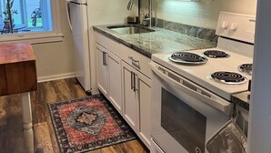 A kitchen with white cabinets, a stainless steel sink, a built-in microwave, and a stove.